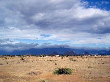 The picture shows a location in India that is very dry and arid. Notice the tall mountains in the ba