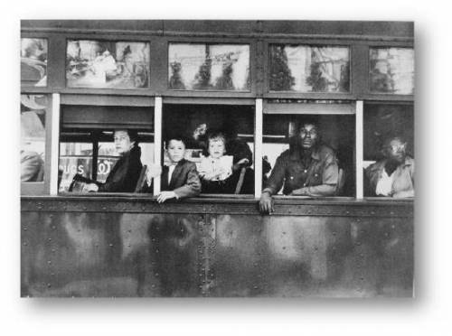 Trolley–New Orleans by Robert Frank. People in a trolley look out of the windows at the people belo